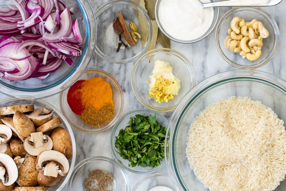 ingredients for vegan mushroom biryani on a marble countertop