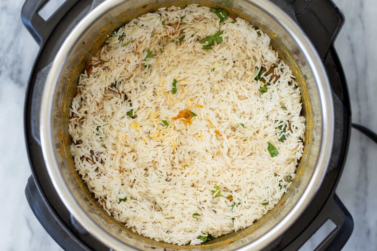 drained soaked rice being added to an Instant Pot with mushrooms and spices