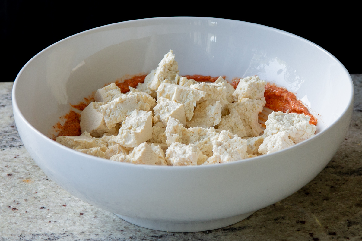 adding tofu to the bowl with the seasoned yogurt mixture