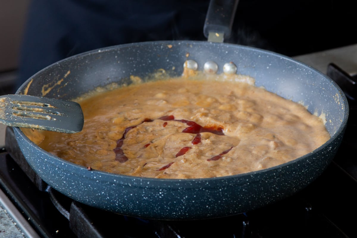 adding tomato paste to the sauce