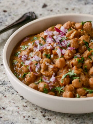 Punjabi chole in a bowl with rice, onion, and cilantro