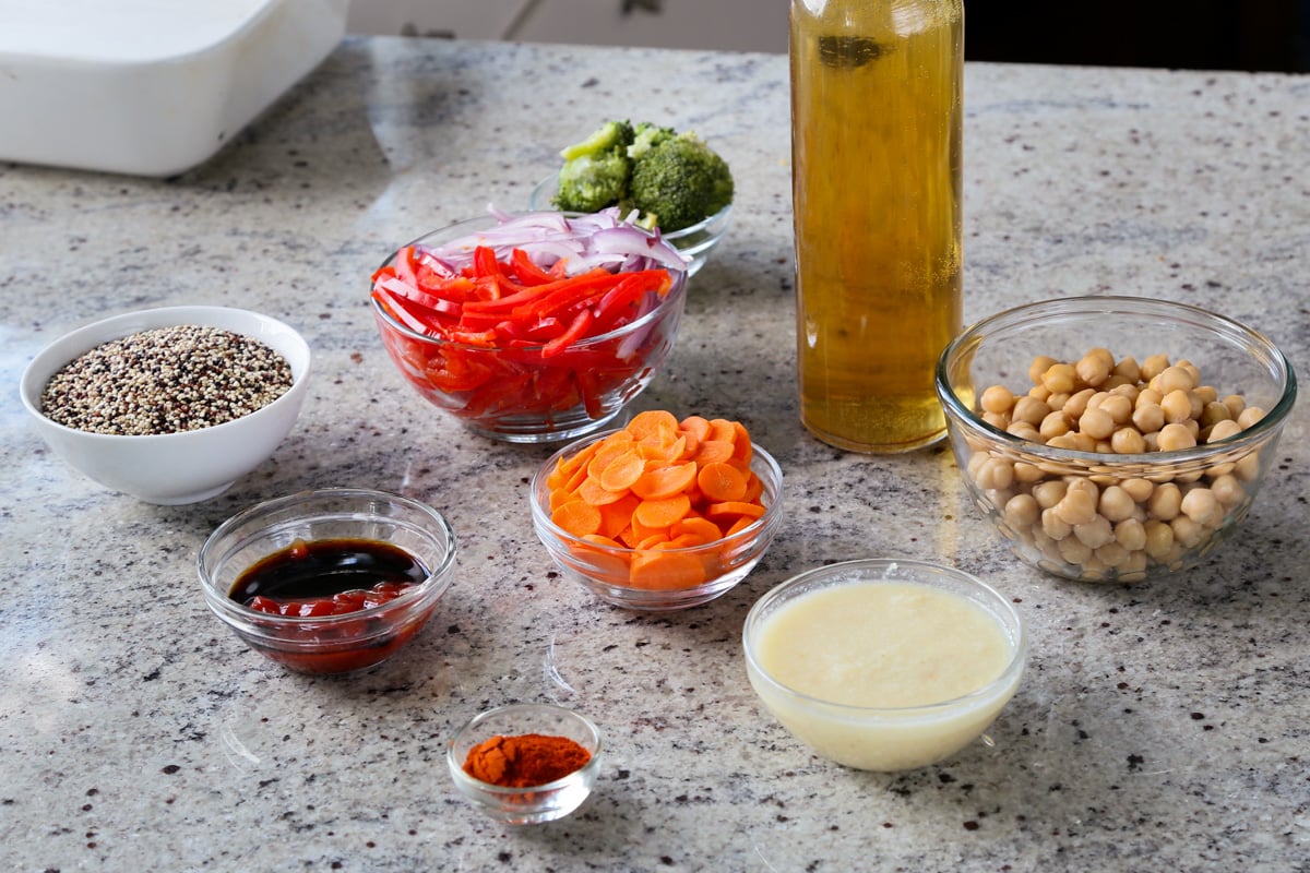 quinoa, broth, and other casserole ingredients in bowls on a kitchen counter