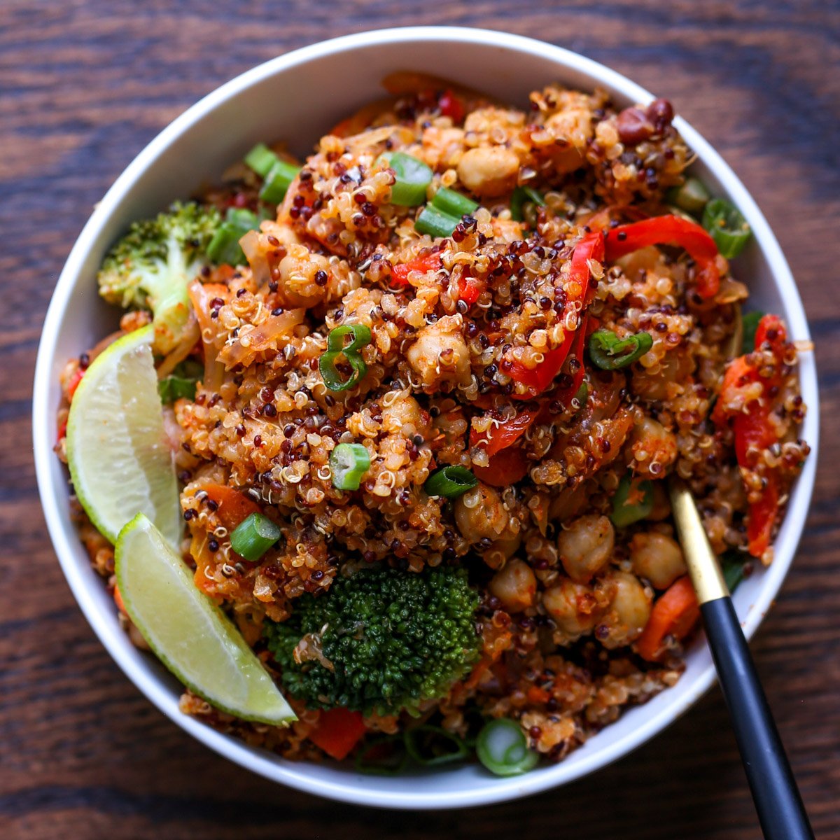 quinoa chickpea casserole in a bowl with lime wedge and green onion
