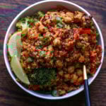 quinoa chickpea casserole in a bowl with lime wedge and green onion