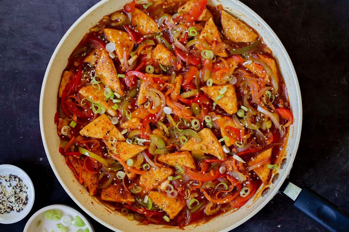 Szechuan tofu in the pan with green onions and sesame seeds