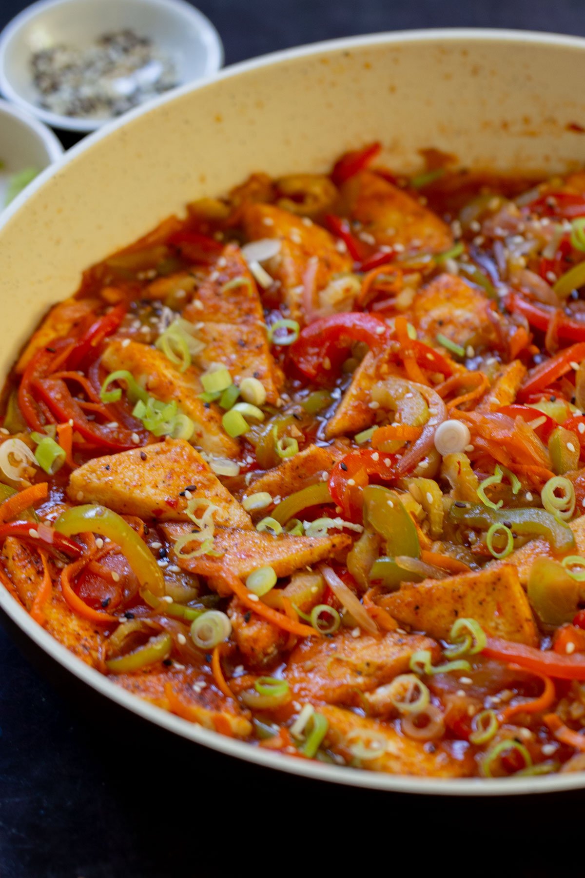 close-up of Szechuan tofu in the pan with green onions and sesame seeds