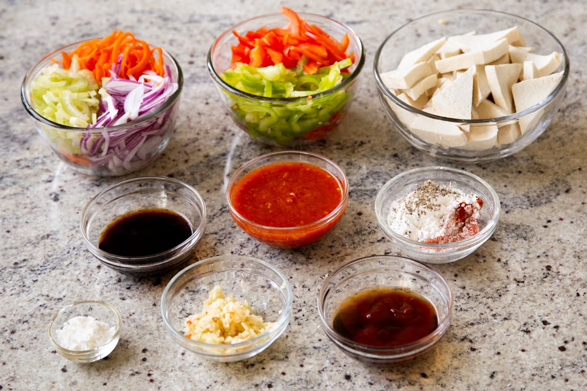 tofu, Szechuan sauce, and other stir fry ingredients in bowls on the kitchen counter