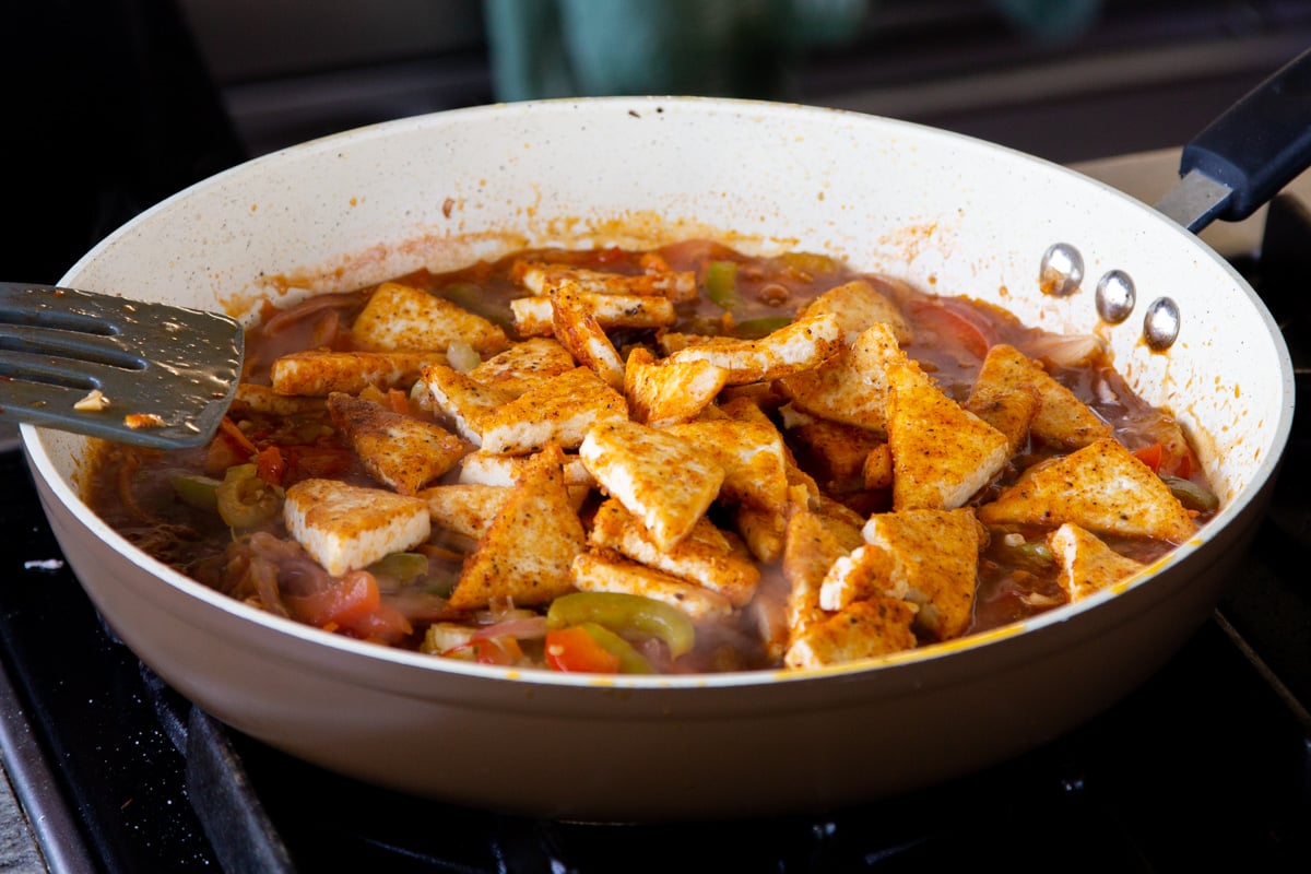 adding tofu to the pan of Szechuan sauce and veggies
