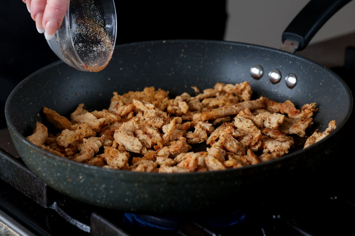 adding spices to the crisped up soy curls in the pan