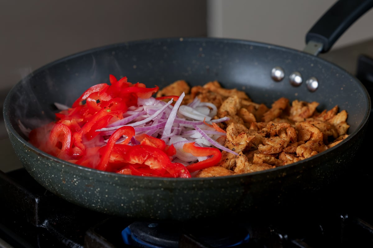 adding onion and pepper to the pan of soy curls