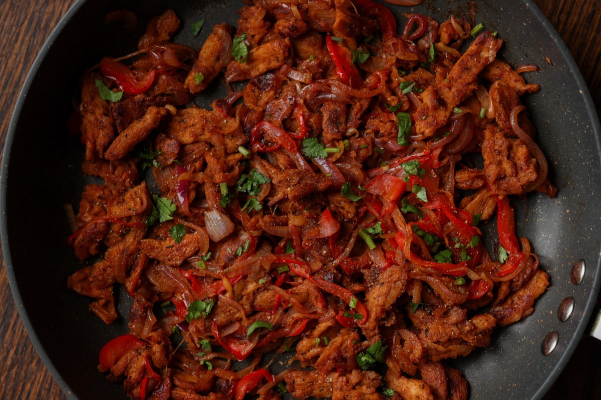 soy curls, peppers, and onions in the pan, after cooking with the sauces