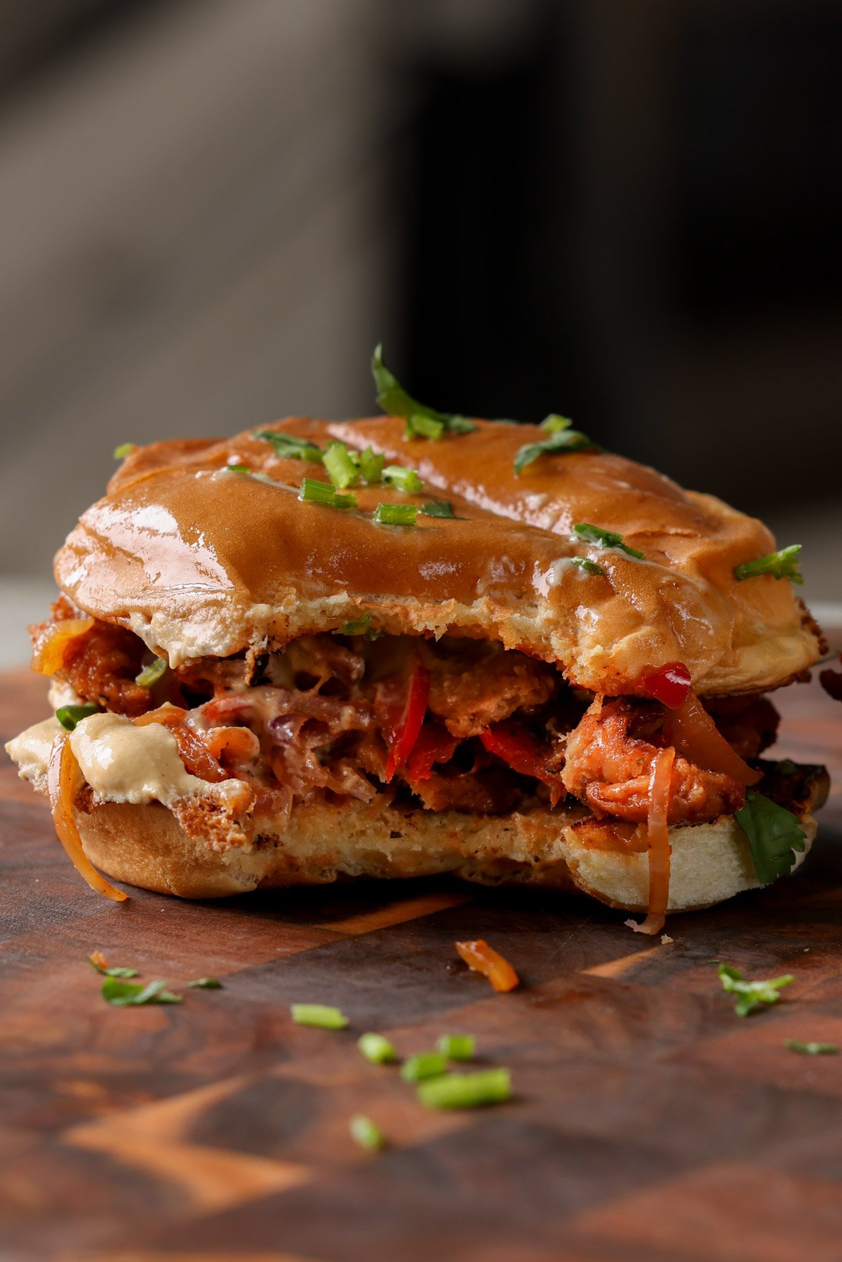vegan cheesesteak sandwich on a cutting board with a bite taken out