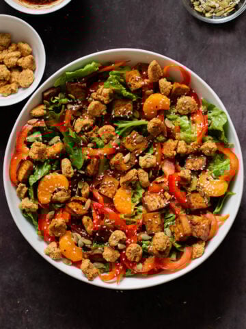 vegan summer salad in a bowl with tofu, croutons, veggies and oranges