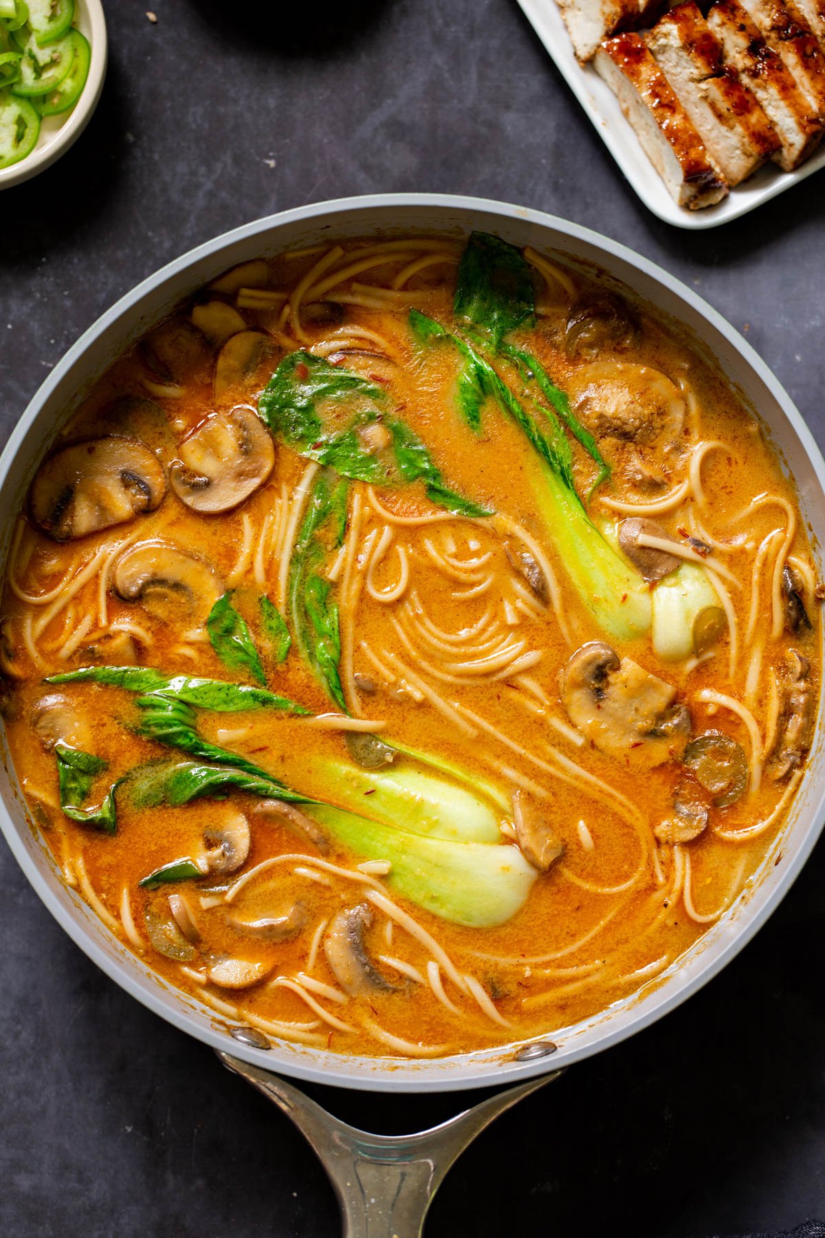 vegan tonkotsu in the pan next to the plate of seared tofu