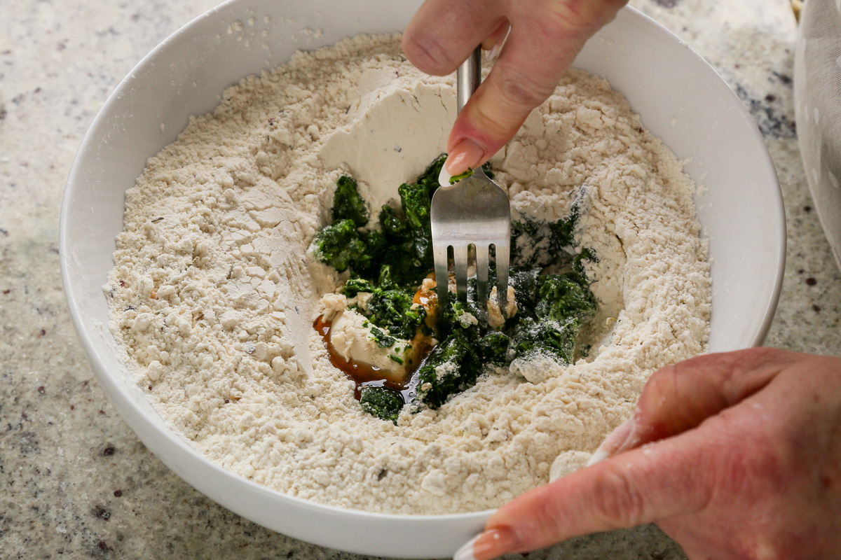 mixing vegan cream cheese and spinach together