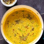 close-up of thecha dal in the skillet next to the mortar of thecha