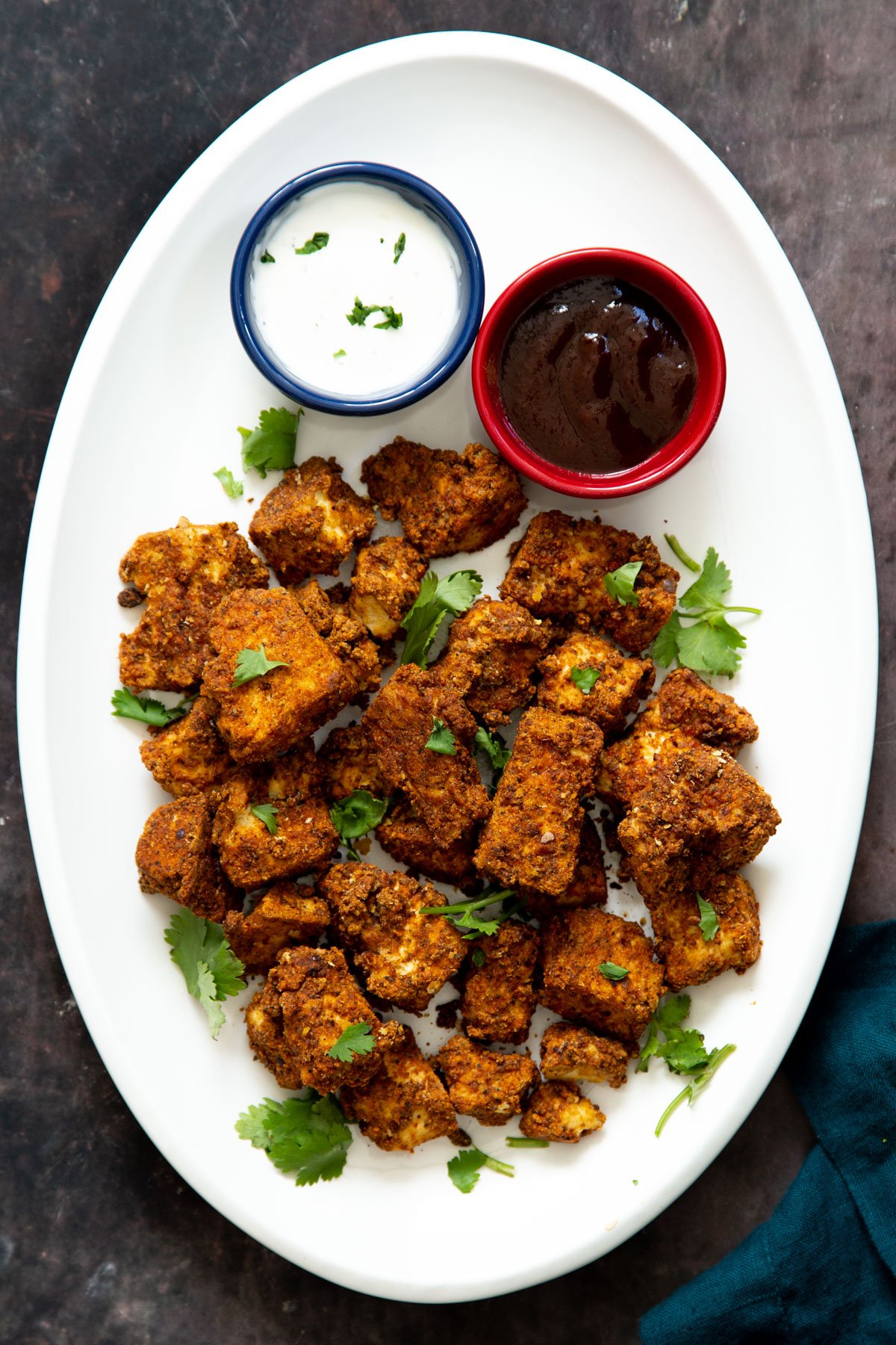 vegan baked tofu nuggets on a white plate with two different dips 