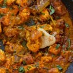 close-up of dipping flatbread into tofu pepper fry in the skillet