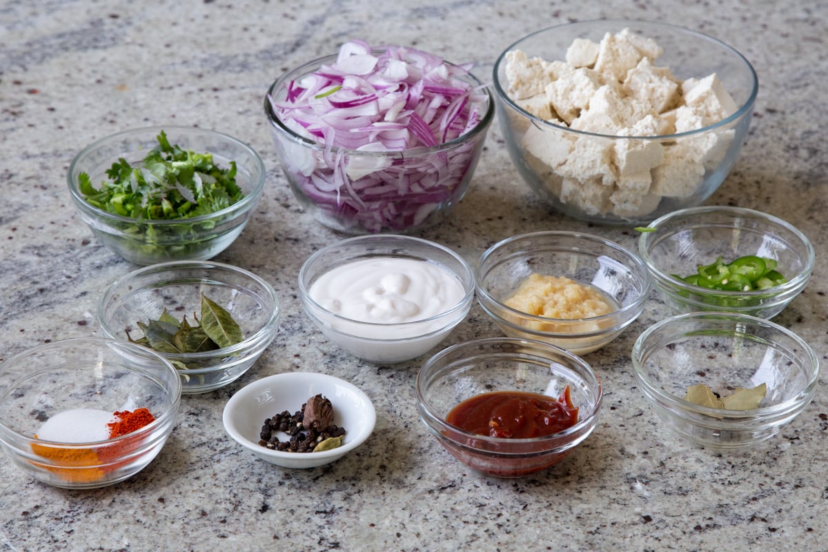 tofu, peppers, onion, and other curry ingredients in bowls on a kitchen counter