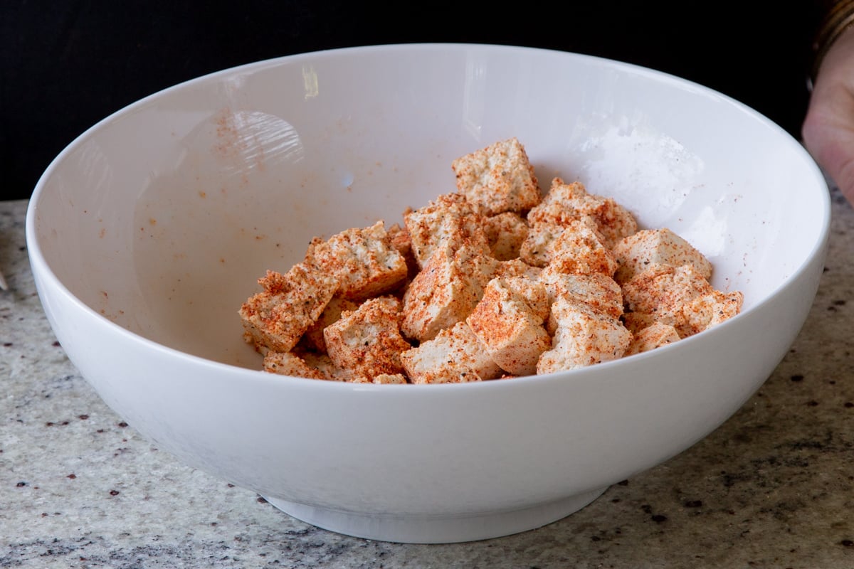 torn up tofu in the bowl after tossing with spices and cornstarch
