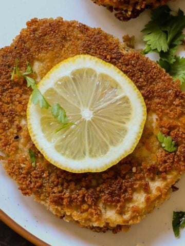 tofu schnitzel on a plate with salad and lemon