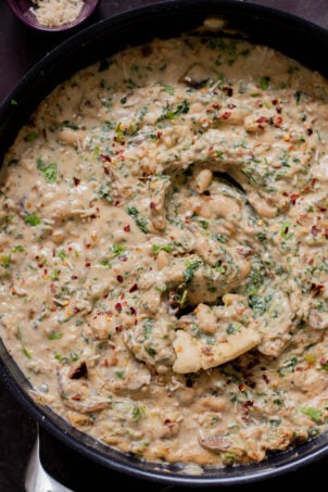 close-up of a panful of Tuscan beans with a piece of flatbread dipped into it