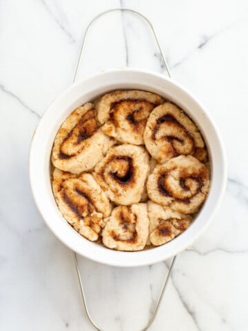 Our Vegan Gluten free Cinnamon rolls in a stoneware dish on marble