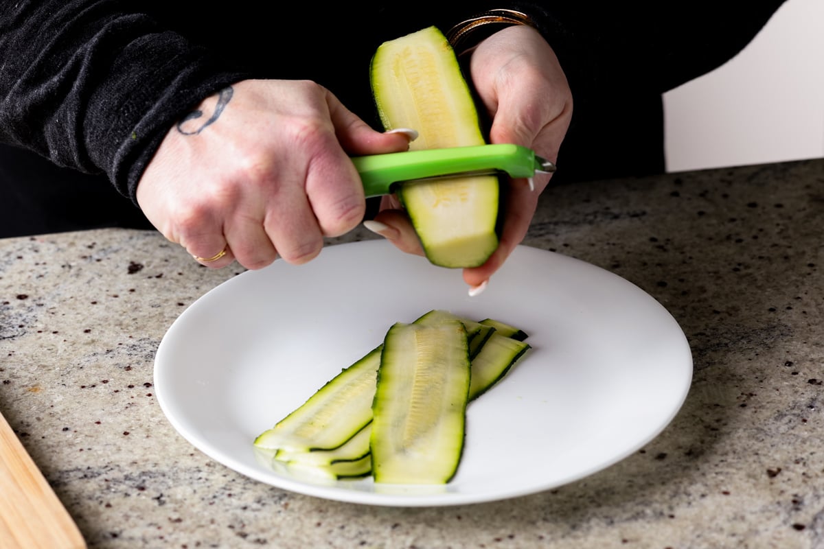 slicing zucchini with a vegetable peeler