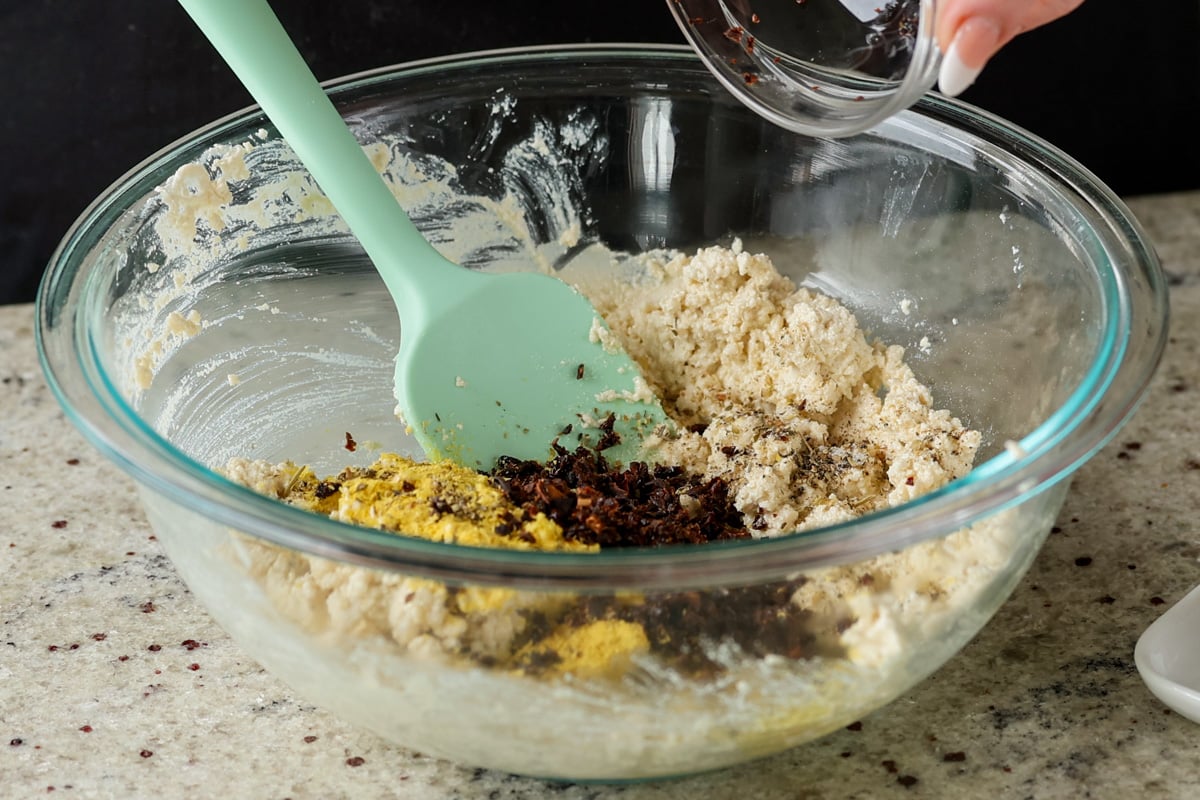 adding spices and sun dried tomato to the tofu mixture
