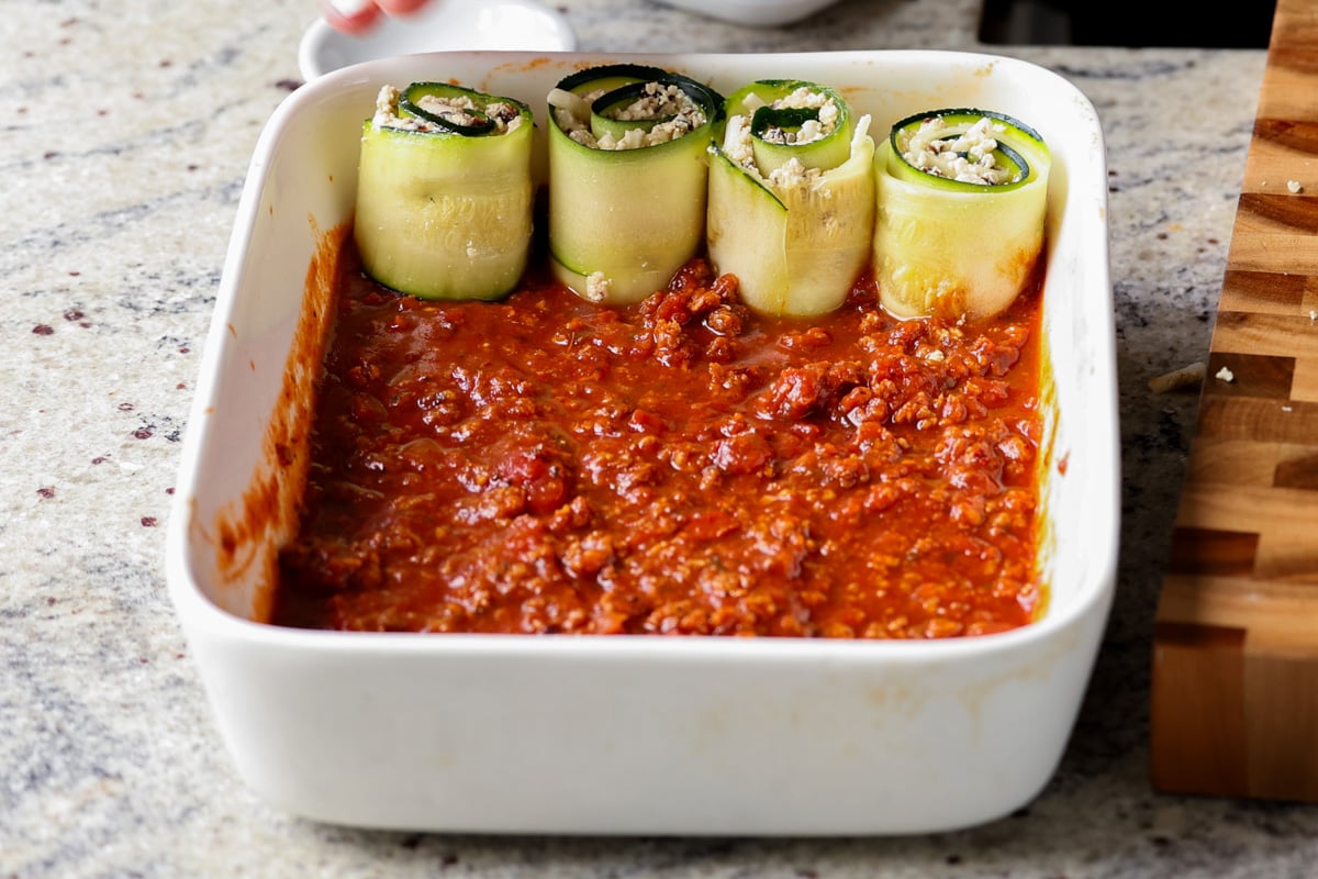 arranging the first few zucchini rolls in the baking dish